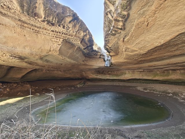 Замёрзшее озерцо в гроте Каракабака зимой: лёд затянул воду под каменным козырьком.