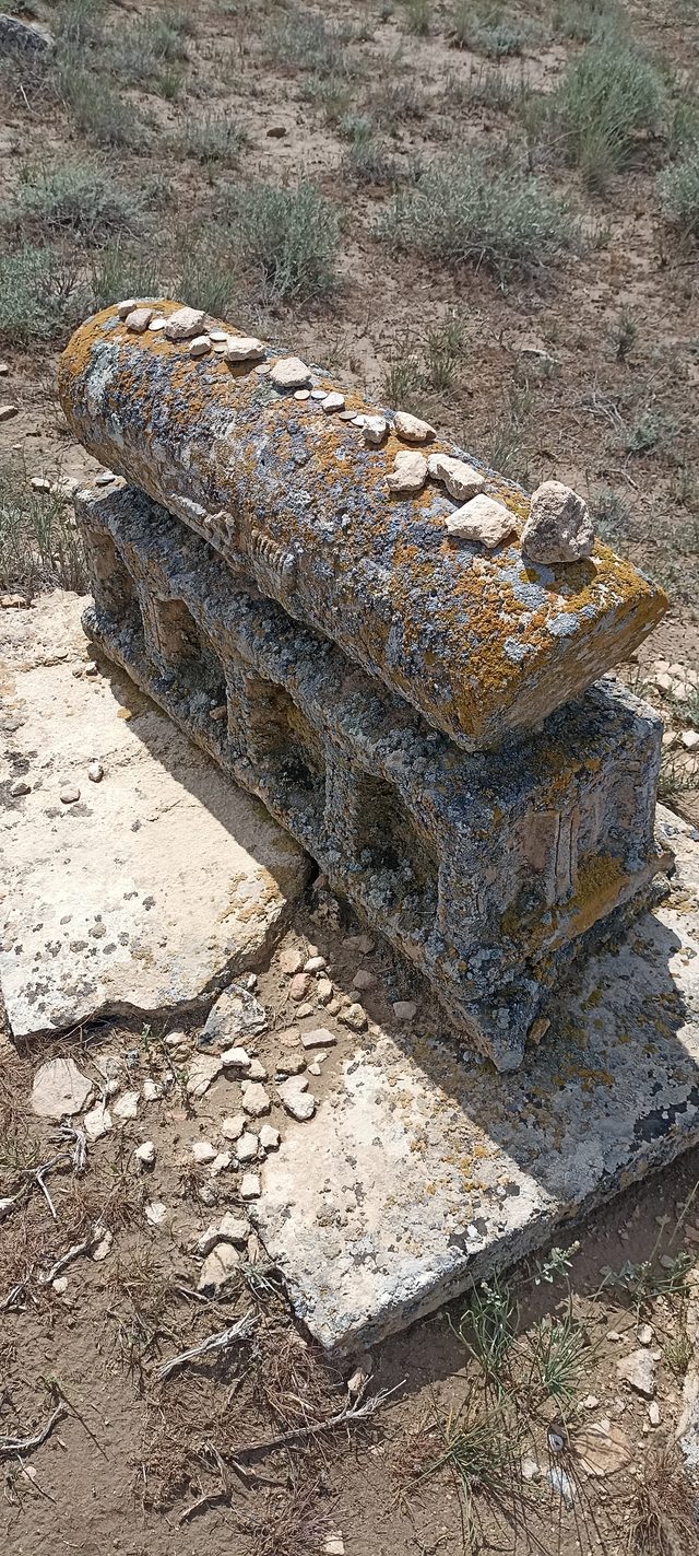 Резное надгробие-сандыктас в некрополе Караман-Ата, покрытое жёлтым лишайником и камешками паломников.