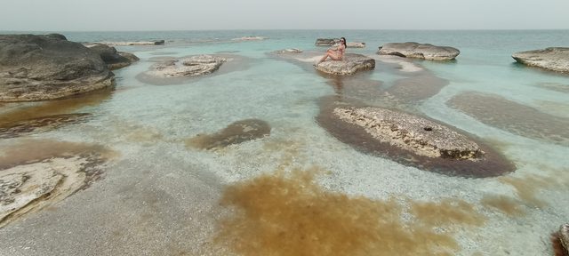 Гостья тура на каменной плите среди природных ванн Майкин кургана в летний зной.