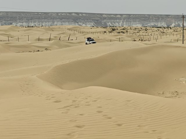 Пески Сенека у кромки чинка: белые обрывы плато замыкают горизонт за дюнами.