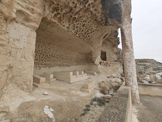 Открытая галерея Шакпак-Ата: сотовое выветривание изъело свод над каменными надгробиями.