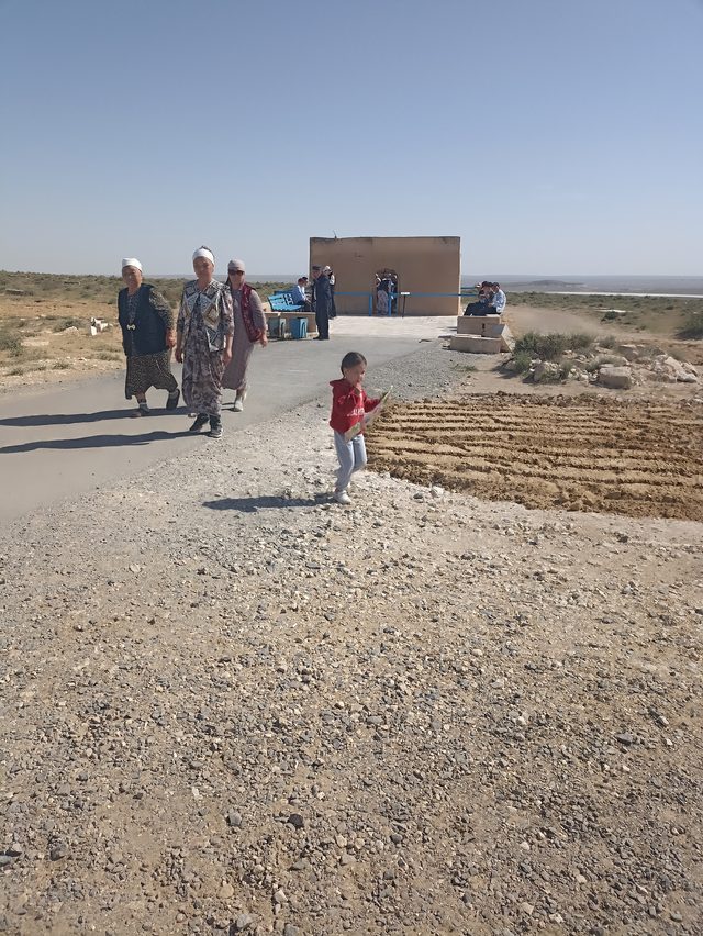 Паломники идут по дороге к подземной мечети Шопан-Ата в жаркий день.