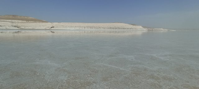 Разлив воды на Тузбаире: белая стена чинка удваивается в зеркальной глади.