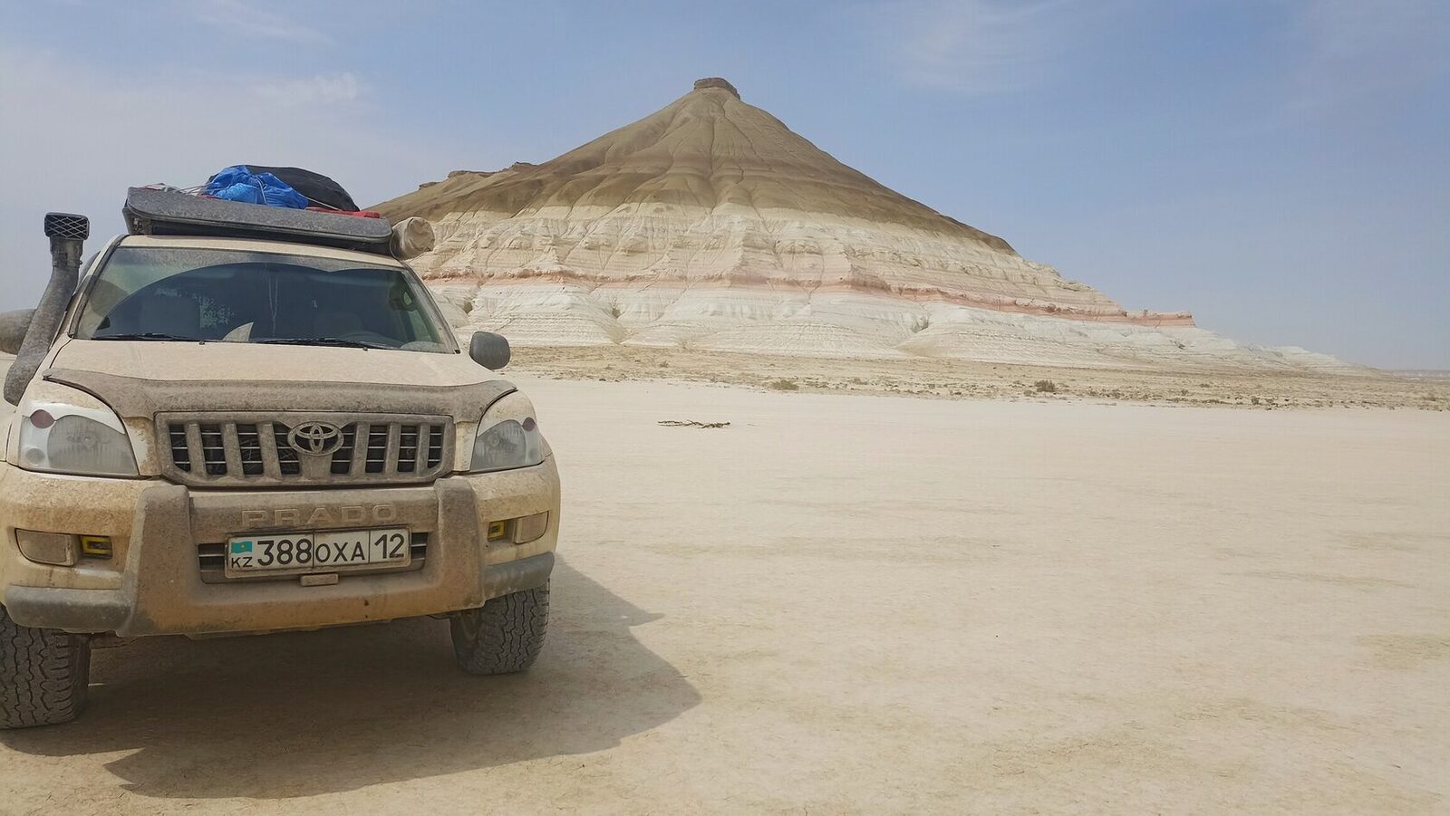 Экспедиционный Toyota Land Cruiser с багажником на крыше у подножия слоистой горы