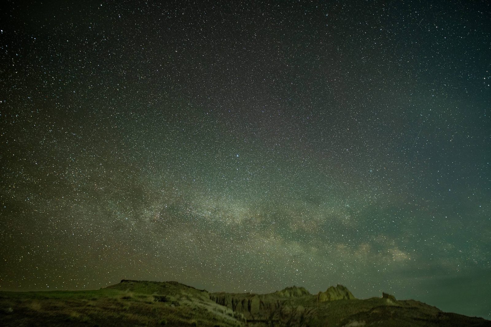 Звёздное небо с зелёным свечением airglow над тёмным гребнем чинка.